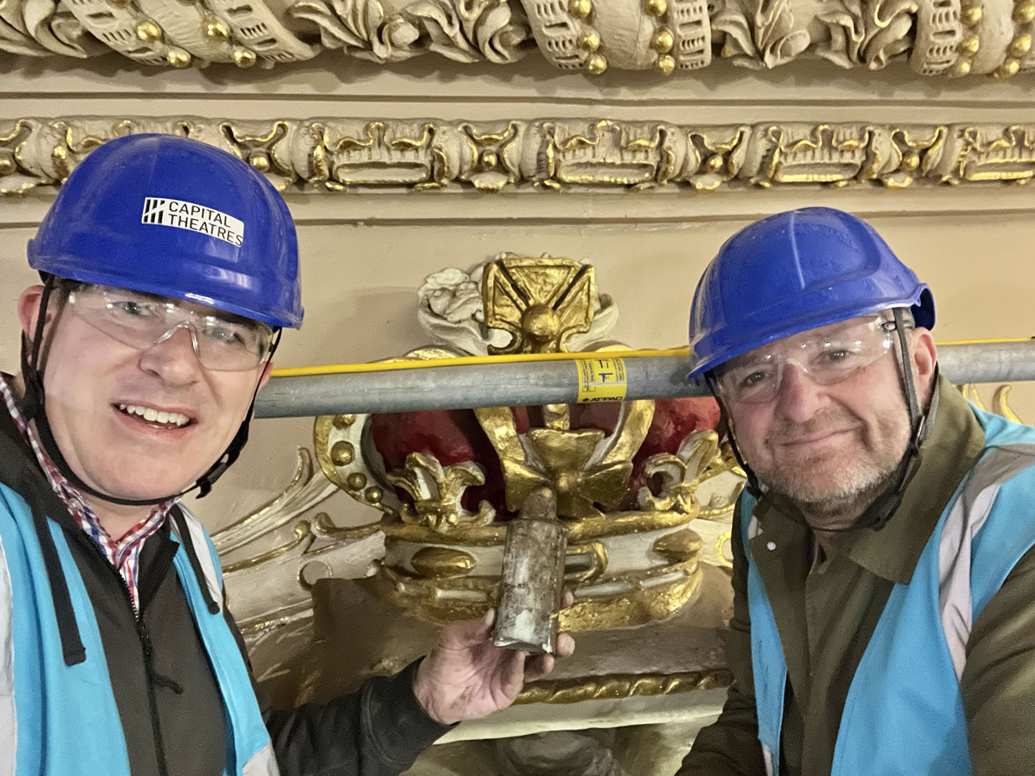 Mike discovers the hidden bottle and poses with John Robb of Capital Theatres to celebrate the find from inside the plaster crown directly behind.